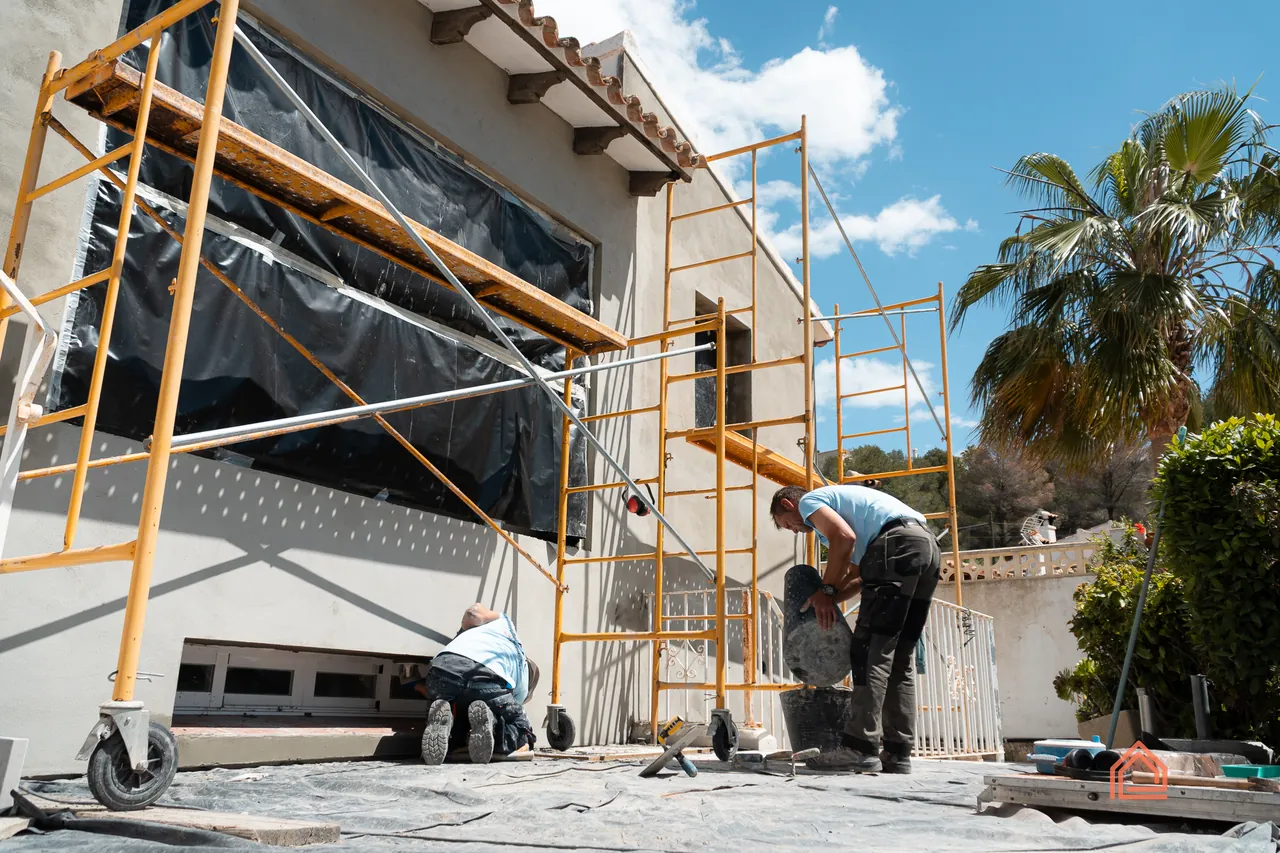 BRC builder working from scaffolding during a villa facade renovation