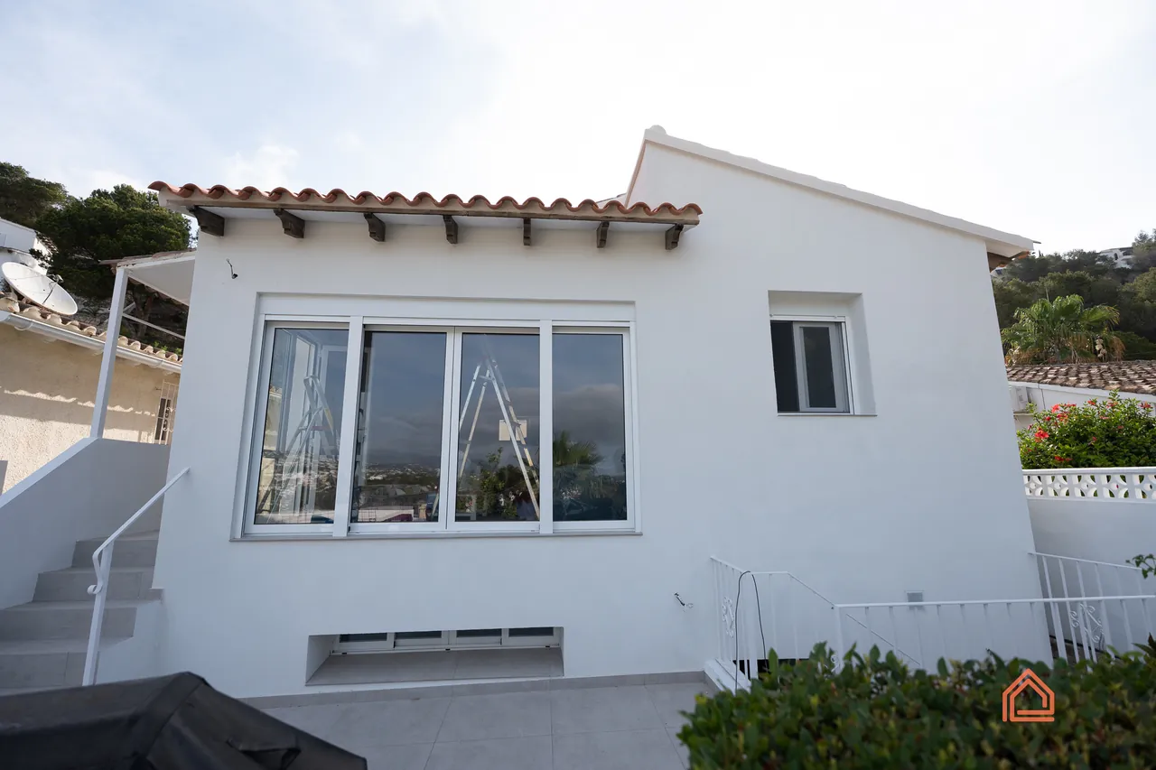 Finished white villa exterior with new picture window, steps and garden planting