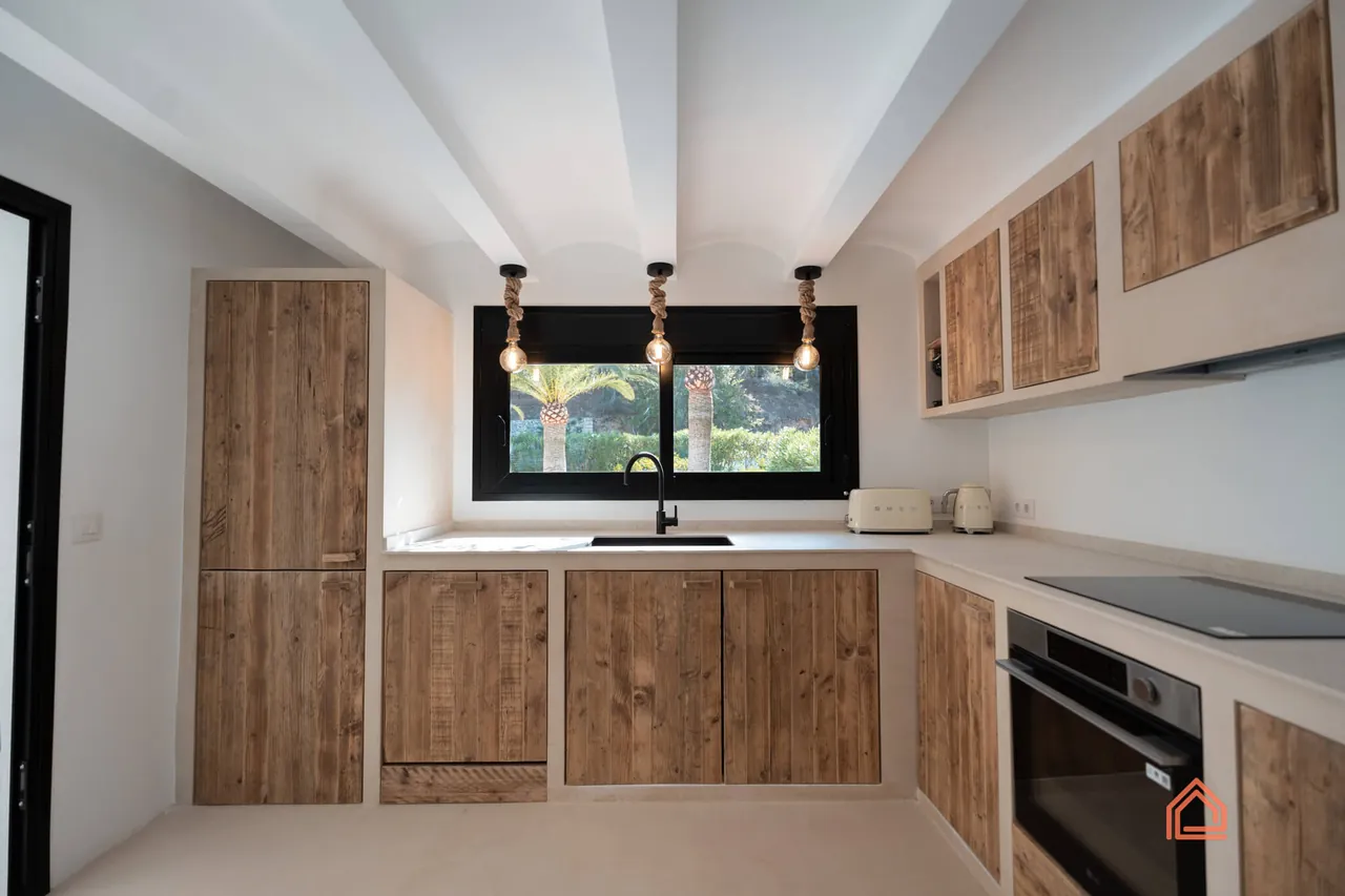Kitchen with reclaimed wood cabinets, black-framed window and pendant lights