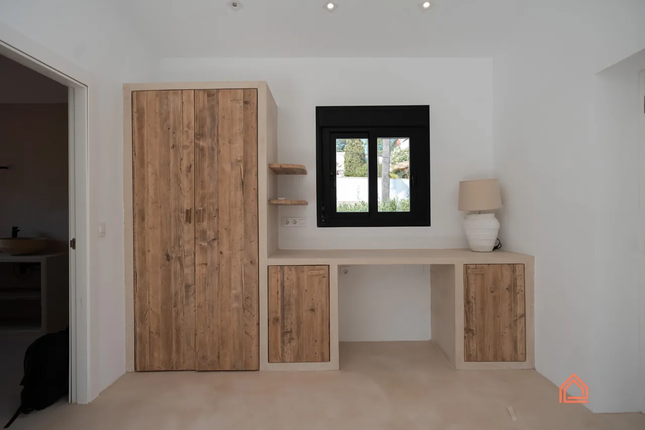 Built-in reclaimed wood wardrobe and desk in a white bedroom