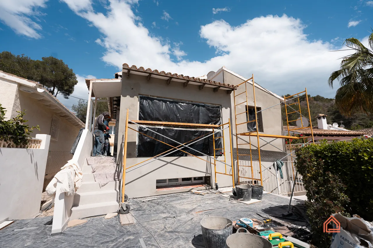 Villa front during renovation with scaffolding and protective sheeting