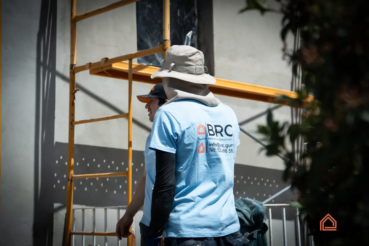 BRC team member in a branded shirt on scaffolding during exterior works