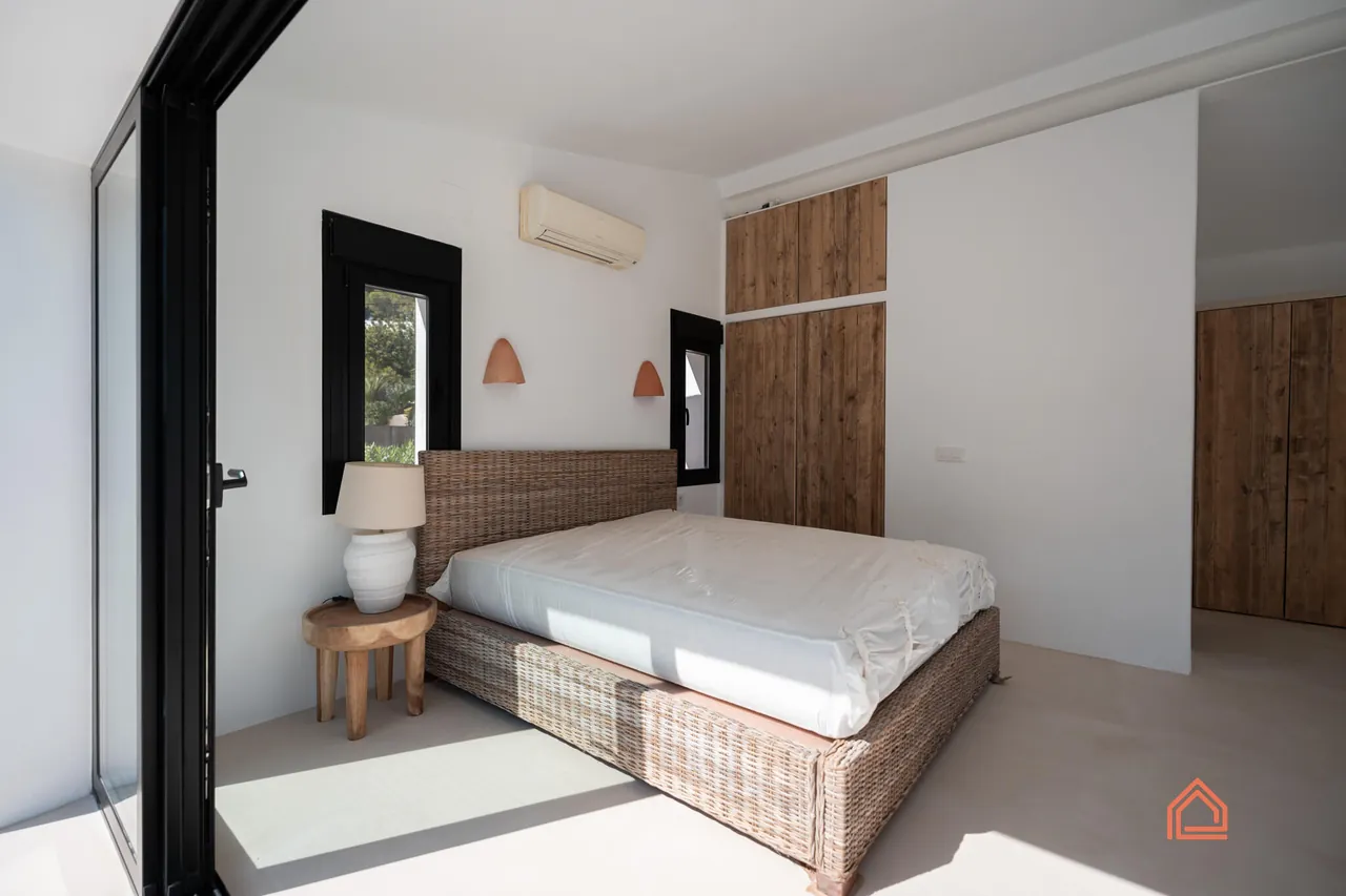 Bedroom with rattan bed, terracotta wall lights and wooden wardrobe