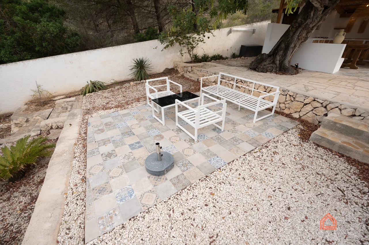 Patterned tile patio with white outdoor furniture in a gravel garden