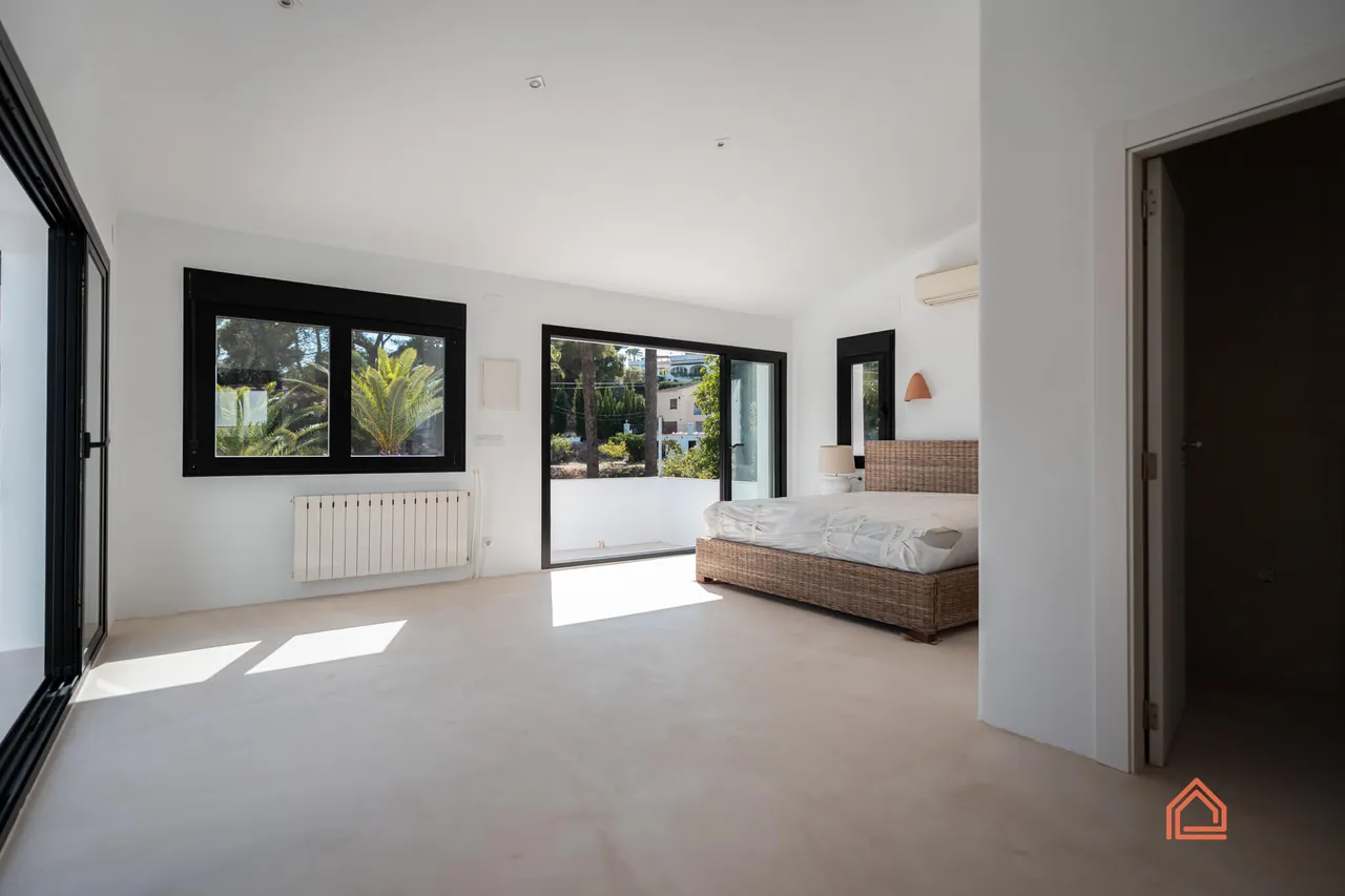 Bright bedroom with microcement floor and black-framed sliding doors