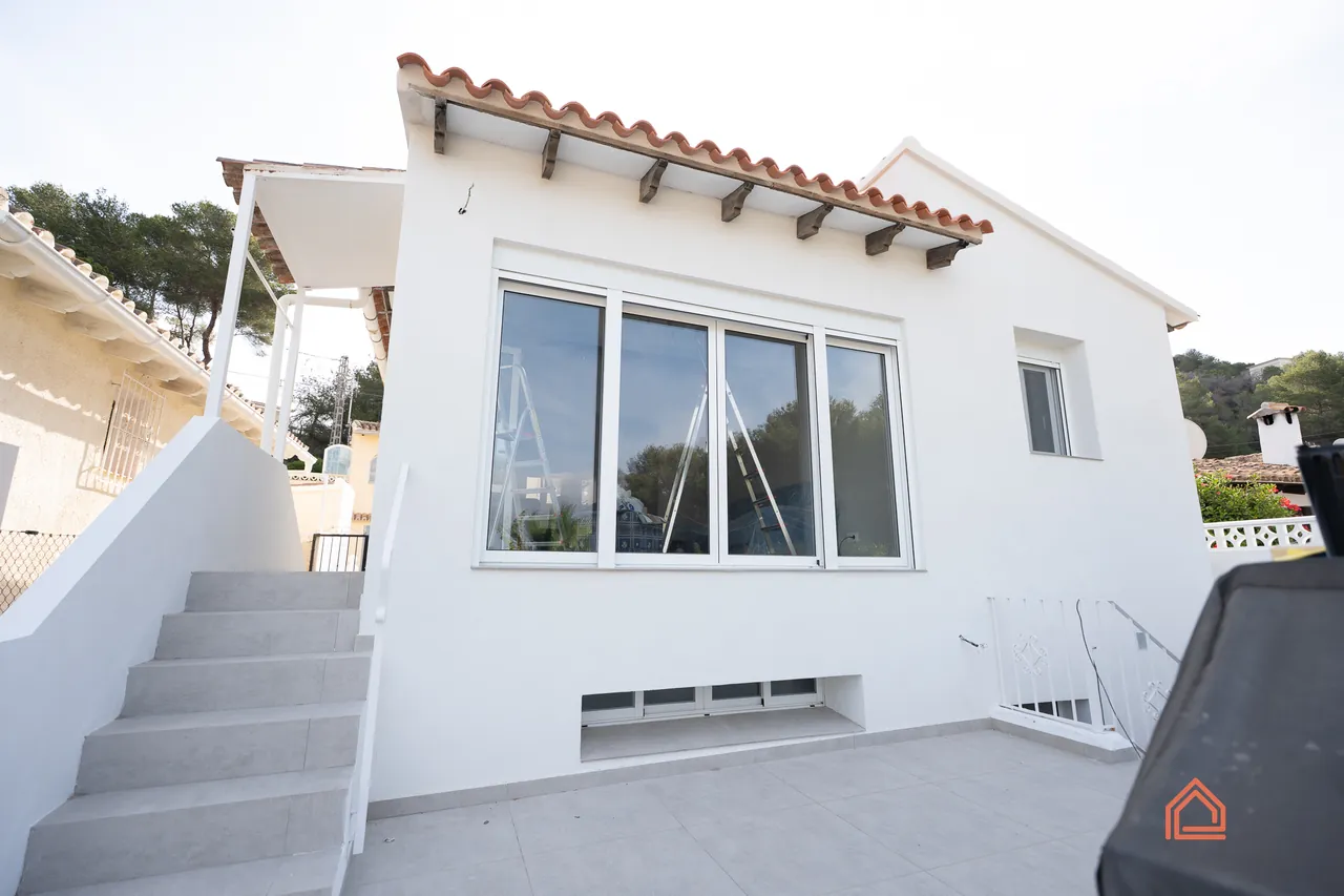 Renovated white single-storey villa with new windows and rendered exterior steps