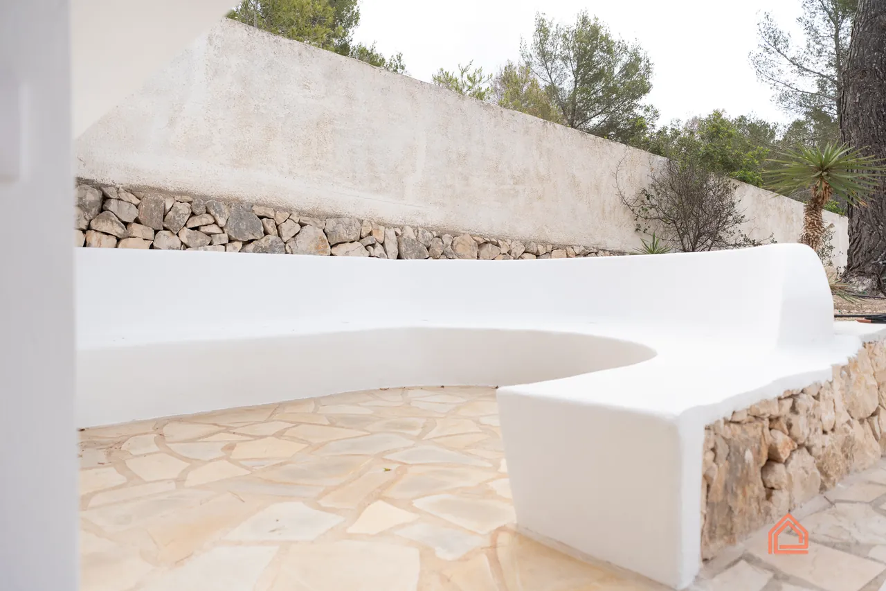 Curved white rendered bench wall beside a natural stone terrace